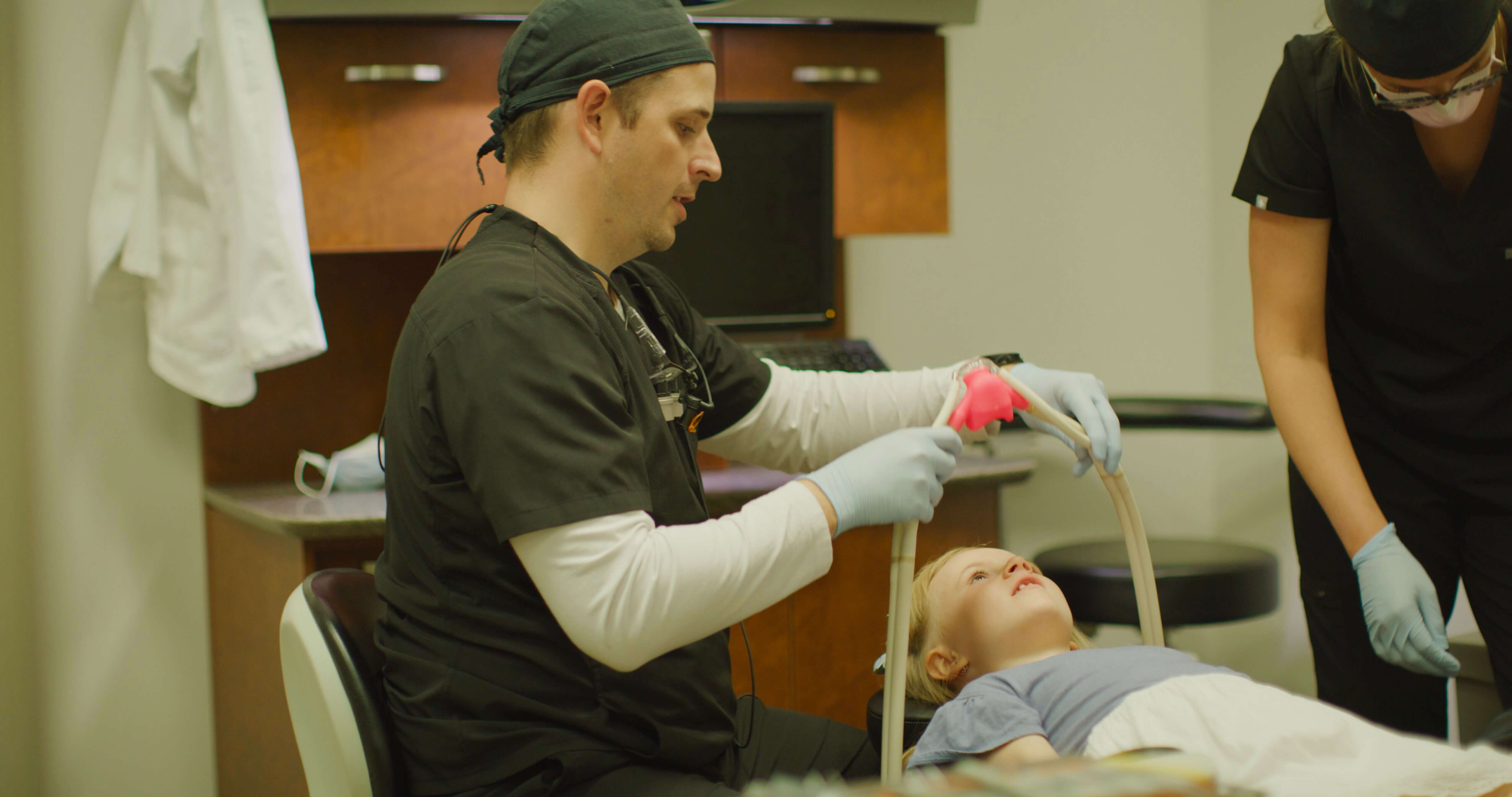 Dentist putting a sedation mask on a child